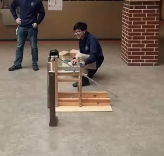 The team testing the wooden trebuchet outdoors